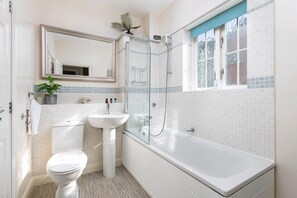 Un baño con inodoro, lavamanos y bañera, un espejo y una ventana con vistas.