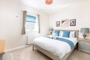 A bedroom with a bed, bedside tables, a window with curtains, and wall art.