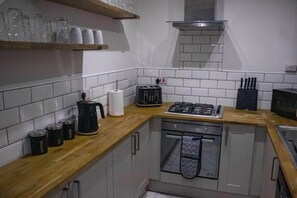 Eine kleine Küche mit Gaskochfeld, Toaster und Kaffeemaschine auf der Arbeitsfläche.