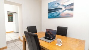 A conference room with a wooden table, two black chairs, a laptop, and a white mug. - Spacious & Comfortable 2-bedroom Home (Swansea)