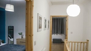 A bedroom with a bed, bedside table, and a hanging light fixture. - Spacious & Comfortable 2-bedroom Home (Swansea)