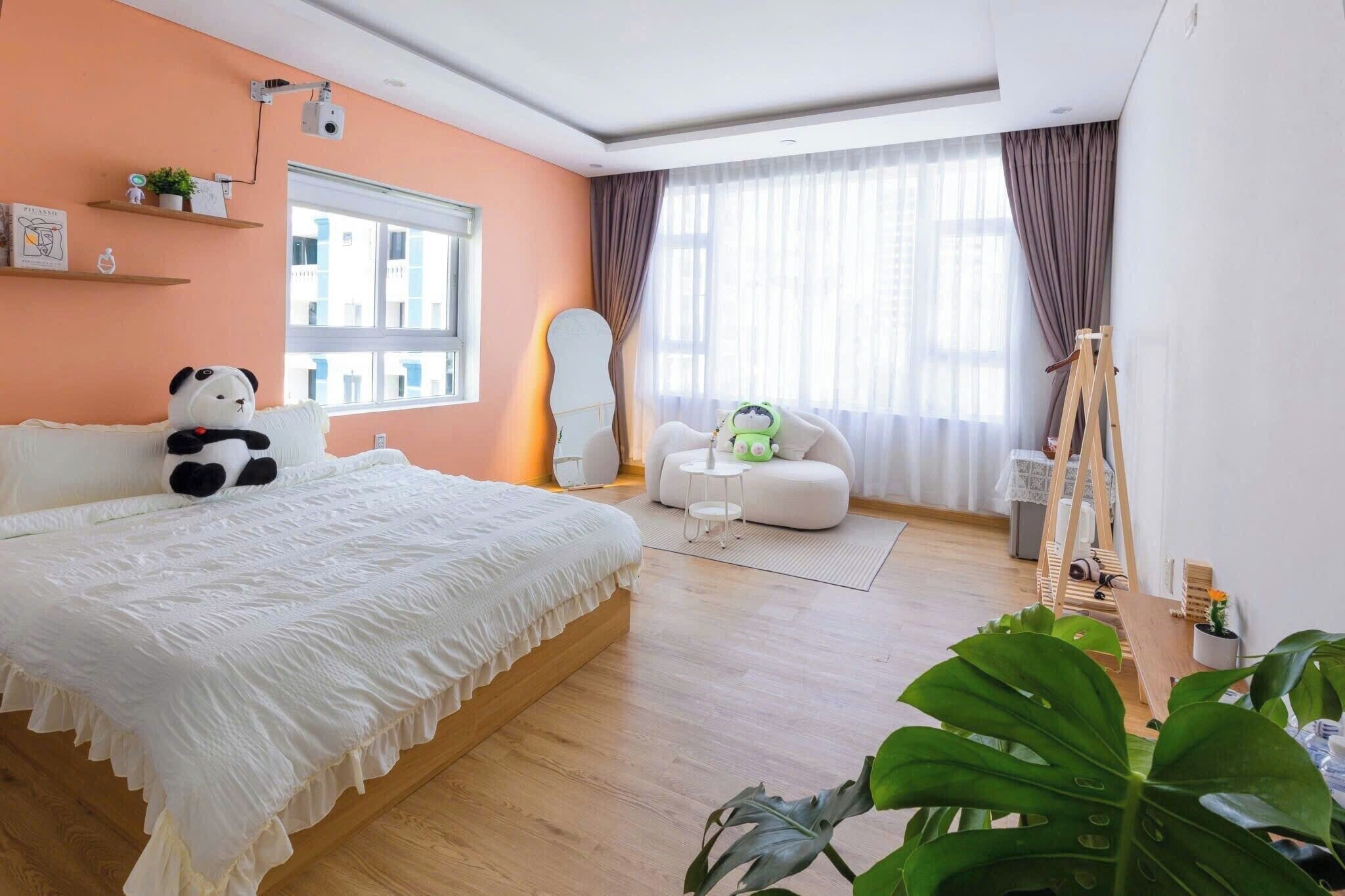 A bedroom with a bed, a sofa, a desk, and a large window.