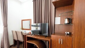 A hotel room with a wooden desk, a television, a cabinet with shelves, and a chair. - BEAR HOTEL & HOMESTAY 2 (Da Nang)