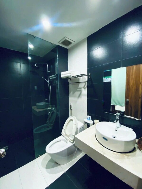 A modern bathroom with a glass-enclosed shower, a white toilet, and a sink with a mirror above it. - BEAR HOTEL & HOMESTAY 2 (Da Nang)