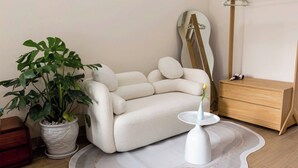 A modern living room with a white sofa, a round coffee table, a potted plant, and a wooden dresser. - BEAR HOTEL & HOMESTAY 2 (Da Nang)