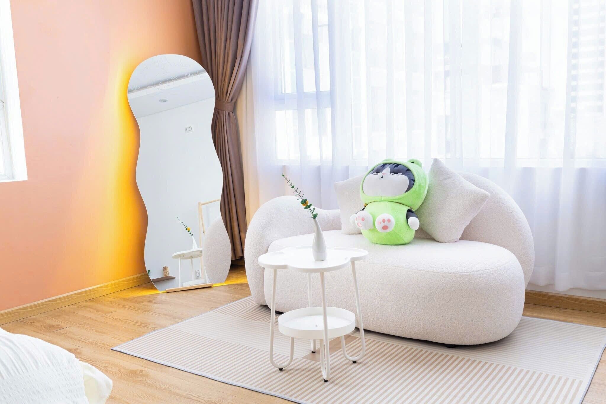 A modern living room with a white sofa, a small round table, and a green plush toy.