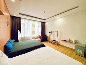 A hotel room with a bed, a chair, a desk, a hanging clothes rack, and a minibar. - BEAR HOTEL & HOMESTAY 2 (Da Nang)