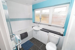 A bathroom with a shower, sink, toilet, and a window. - Comfortable 3-bed, 2-bath Basingstoke Stay (Basingstoke)