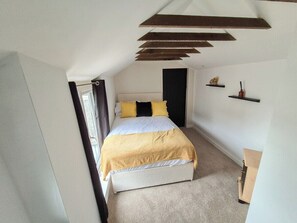 Ein Schlafzimmer mit Bett, Fenster, Tür und einem Regal mit Gegenständen.