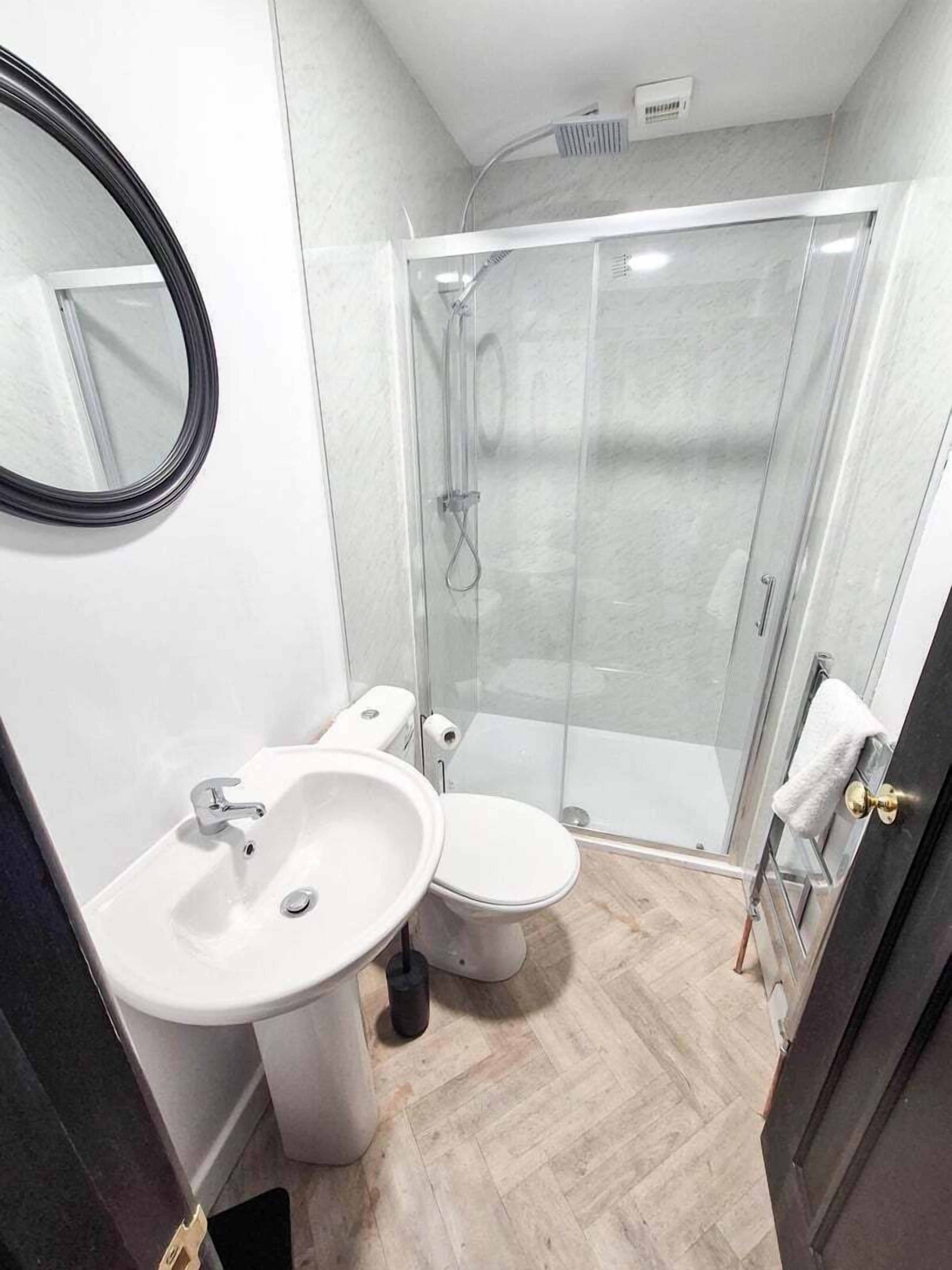 A modern bathroom with a glass-enclosed shower, a double sink vanity, and a toilet.