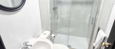 A modern bathroom with a glass-enclosed shower, a double sink vanity, and a toilet.
