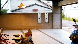 A covered parking area with a tiled floor, a hanging light fixture, and a wall with two decorative panels. - One of seven BnB (Hualien)