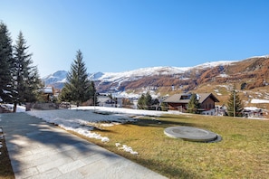 A paved pathway leading to a building with a view of snow-capped mountains.