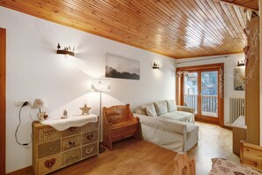 A cozy room with wooden floors, a sofa, a wooden cabinet, and a window with a view.
