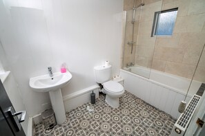 A bathroom with a sink, toilet, shower, and patterned floor tiles. - Cosy 3-bed House Walk to Swansea Stadium (Swansea)