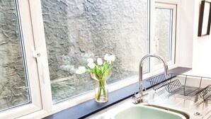 Eine Küche mit einem großen Fenster, einer Spüle und einem Teekessel auf der Arbeitsfläche.