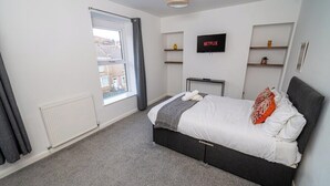 Ein modernes Schlafzimmer mit Bett, Fernseher und Fenster.