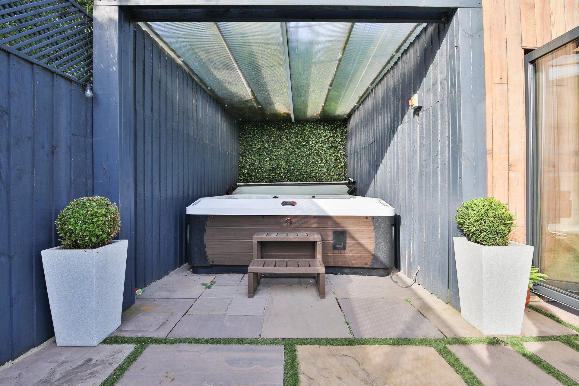 A spa area with a hot tub, wooden bench, and potted plants.