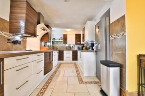 A modern kitchen with white cabinets, a stainless steel refrigerator, and a tiled backsplash. - The Swansea Homestay Spacious 4-bed Retreat (Swansea)