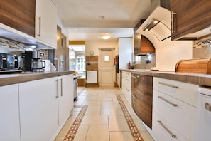 A modern kitchen with white cabinets, stainless steel appliances, and a patterned floor. - The Swansea Homestay Spacious 4-bed Retreat (Swansea)