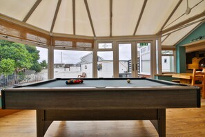 A pool table with balls, a wooden bench, and a view through large windows to the outside. - The Swansea Homestay Spacious 4-bed Retreat (Swansea)