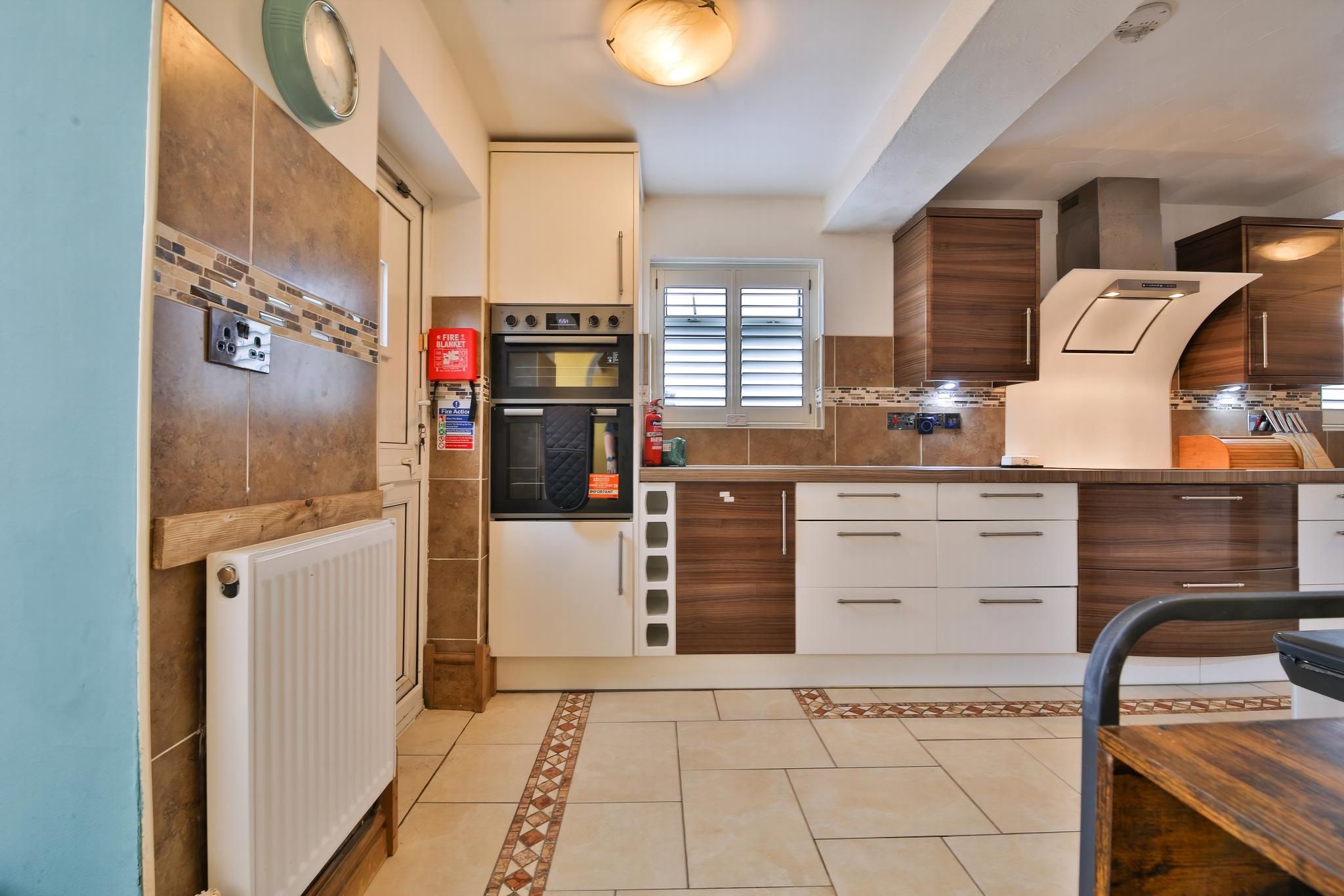 A modern kitchen with a built-in oven, a window, and a white countertop.