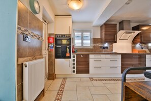 A modern kitchen with a built-in oven, a window, and a white countertop. - The Swansea Homestay Spacious 4-bed Retreat (Swansea)