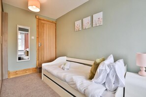 A bedroom with a bed, a wooden door, a mirror, and three floral wall art pieces. - The Swansea Homestay Spacious 4-bed Retreat (Swansea)