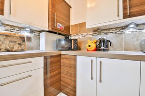 A modern kitchen with wooden cabinets, a microwave, and a coffee maker. - The Swansea Homestay Spacious 4-bed Retreat (Swansea)