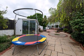 A trampoline in a backyard with a small shed and a paved pathway. - The Swansea Homestay Spacious 4-bed Retreat (Swansea)