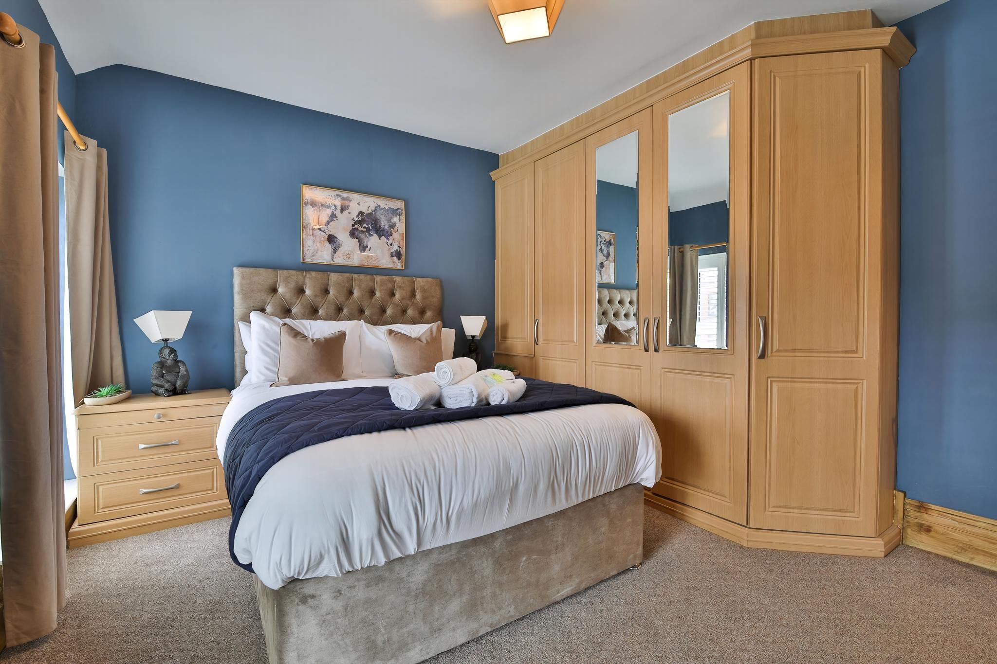 A bedroom with a large bed, a wardrobe, a nightstand, and a lamp.