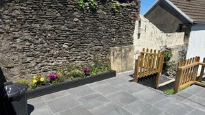 A paved patio area with stone walls and a wooden gate. - Spacious 3BR Swansea House Near City Centre (Swansea)