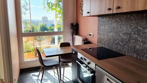 A modern kitchen with a large window, a dining area with two chairs, and a view of the cityscape.