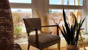 A room with a large window, a wicker chair, a potted plant, and a wooden floor. - Urban escape with a view just a stone's throw from the metro (Villeurbanne)