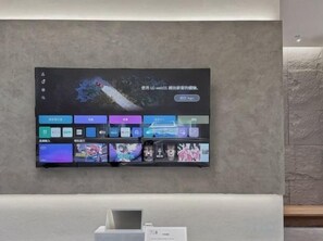 Un téléviseur à écran plat fixé au mur affiche une interface numérique avec divers icônes et une image centrale.