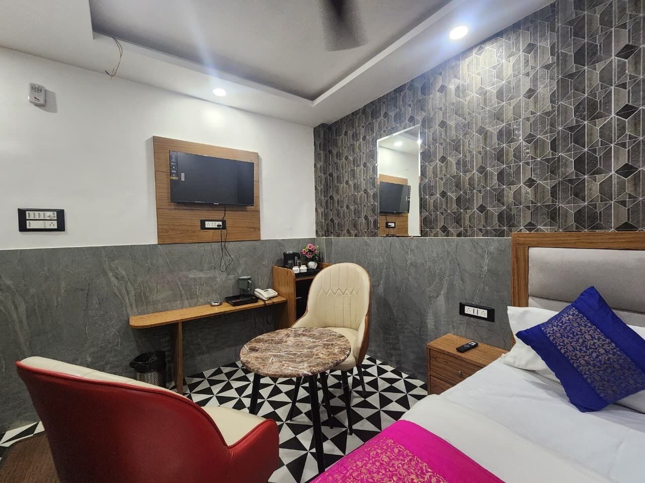 Une chambre d’hôtel équipée d’un lit, d’une chaise, d’un bureau et d’un téléviseur fixé au mur.