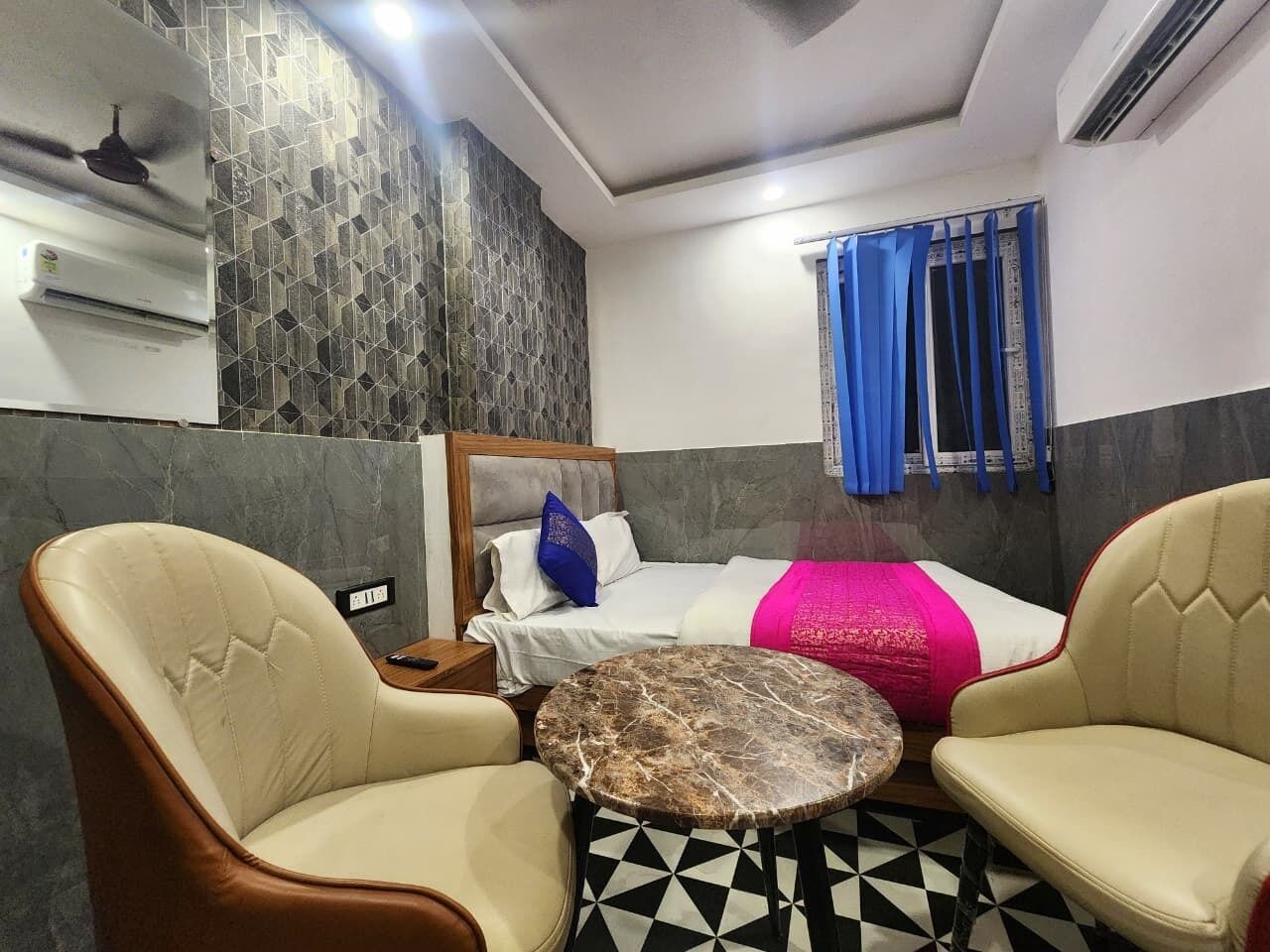 Ein Hotelzimmer mit einem Bett, zwei Sesseln, einem kleinen runden Tisch und einem gestreiften Boden.