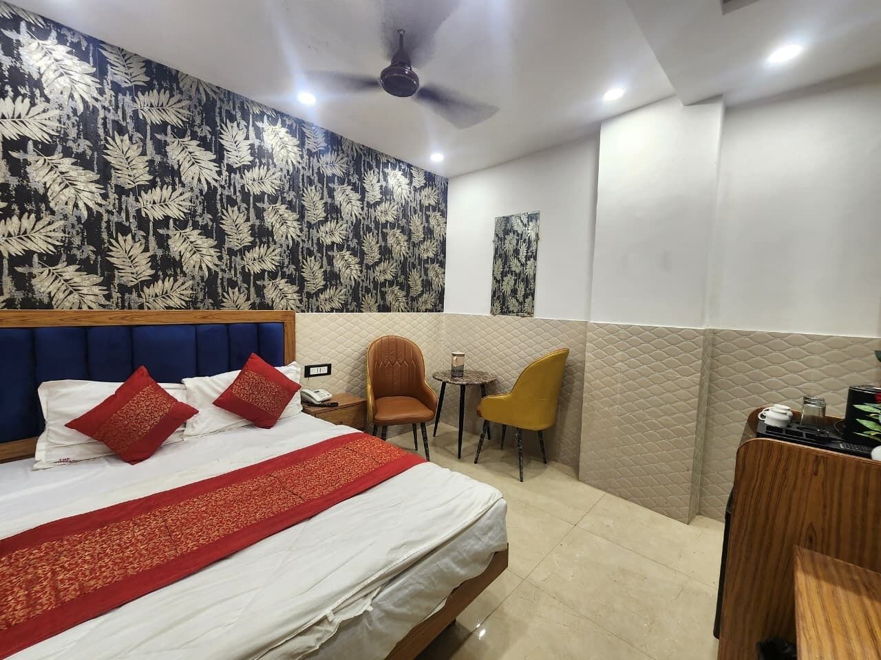 A hotel room with a bed, two chairs, a small table, and a desk with a computer.
