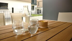 Ett träbord med en vattenflaska, två glas och ett ljus.