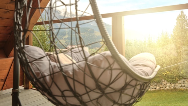 A wooden deck with a hanging hammock chair overlooking a mountainous landscape. - Penthouse Cassiopeia (Tauplitz)