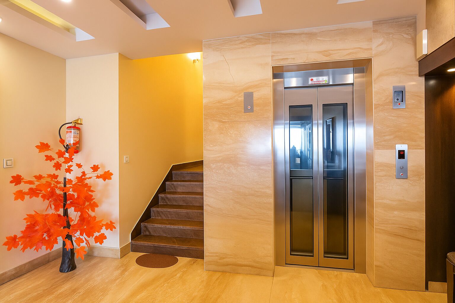 A modern elevator with a digital display, a staircase, and a decorative red maple tree.