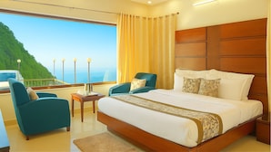 A hotel room with a large bed, two armchairs, a small table, and a view of a mountainous landscape. - Hotel Winter Line Inn Near St Francis Monastery (Mussoorie)