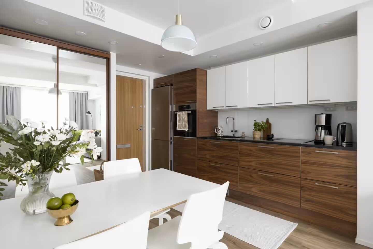 Una cocina moderna con armarios blancos, encimera negra y refrigerador de acero inoxidable.