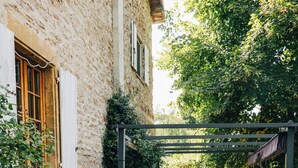 A rustic outdoor patio with stone flooring, wooden tables and chairs, and potted plants. - Domaine de cozance (Anjou)