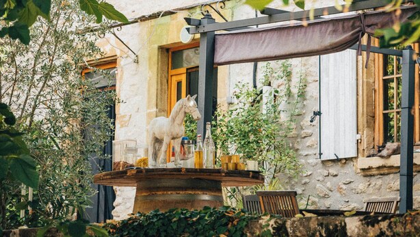 A rustic stone building with a wooden balcony, ivy-covered walls, and outdoor seating. - Domaine de cozance (Anjou)