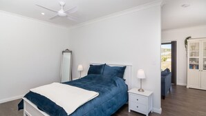 A bedroom with a bed, nightstands, a mirror, and a cabinet.