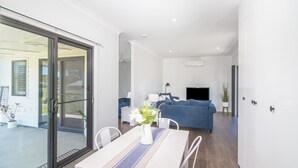 A modern living room with a sofa, a TV, and a dining area with a table and chairs.
