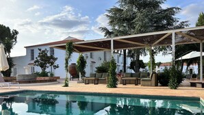 A swimming pool with a tiled edge, surrounded by outdoor furniture and covered seating areas.