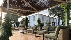 An outdoor patio with hexagonal tiled flooring, wicker furniture, and a covered area with a thatched roof.