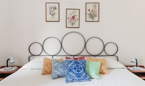 Una cama con cabecera de metal, varias almohadas y mesitas de noche con lámparas.